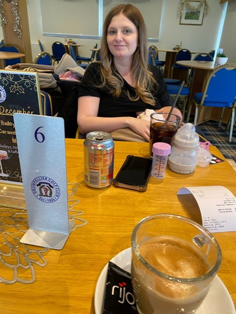 Image of a mum sat at a table at a cafe, breastfeeding her baby.